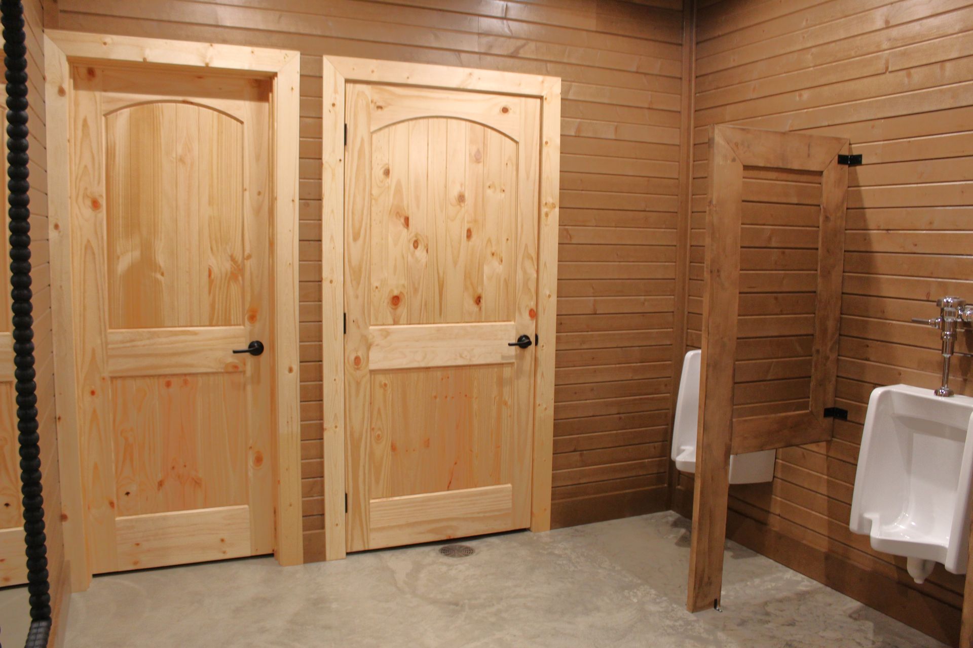 A bathroom with wooden doors and urinals in it