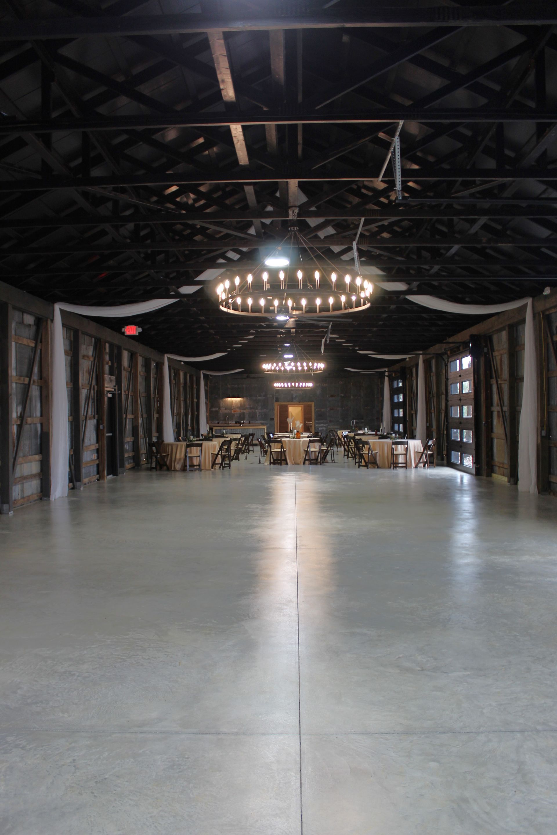 A large open space with tables and chairs and a chandelier hanging from the ceiling.