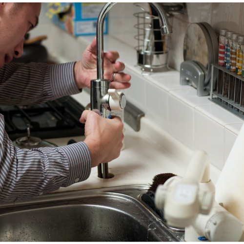 A man is fixing a faucet in a kitchen