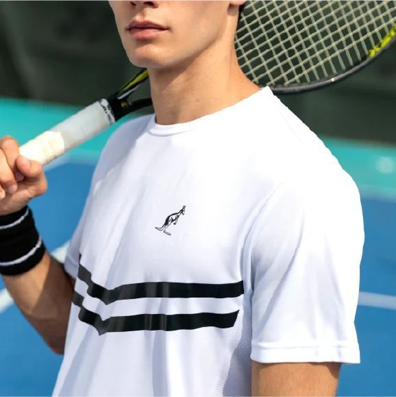 Uomo con maglietta da tennis bianca a strisce nere, che tiene in mano una racchetta da tennis su un campo.