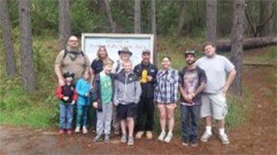 Group of people standing near a sign in a forest.