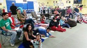 People gathered indoors, some seated in chairs, others on mats. People gathered indoors, some seated in chairs, others on mats.