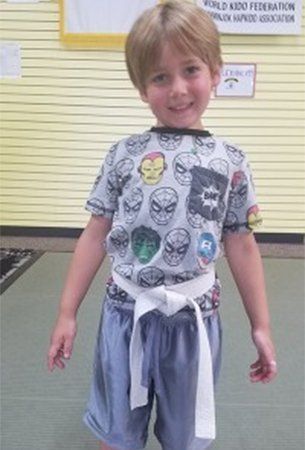Young boy in a superhero shirt and white belt smiling. Young boy in a superhero shirt and white belt smiling.