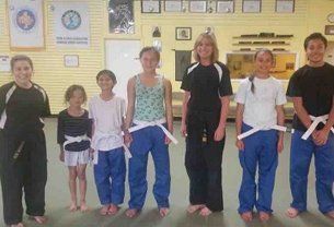 People in martial arts uniforms with white belts standing together.