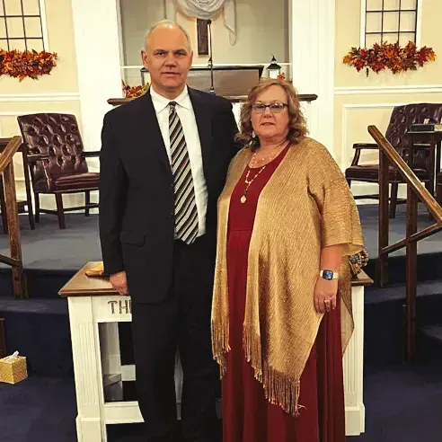 A man and a woman are posing for a picture in a church.