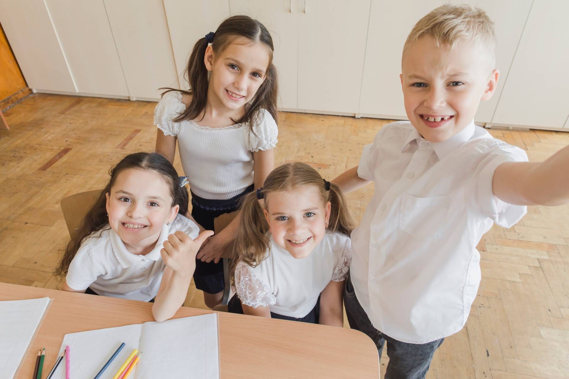 A group of children are sitting at a table in a classroom.