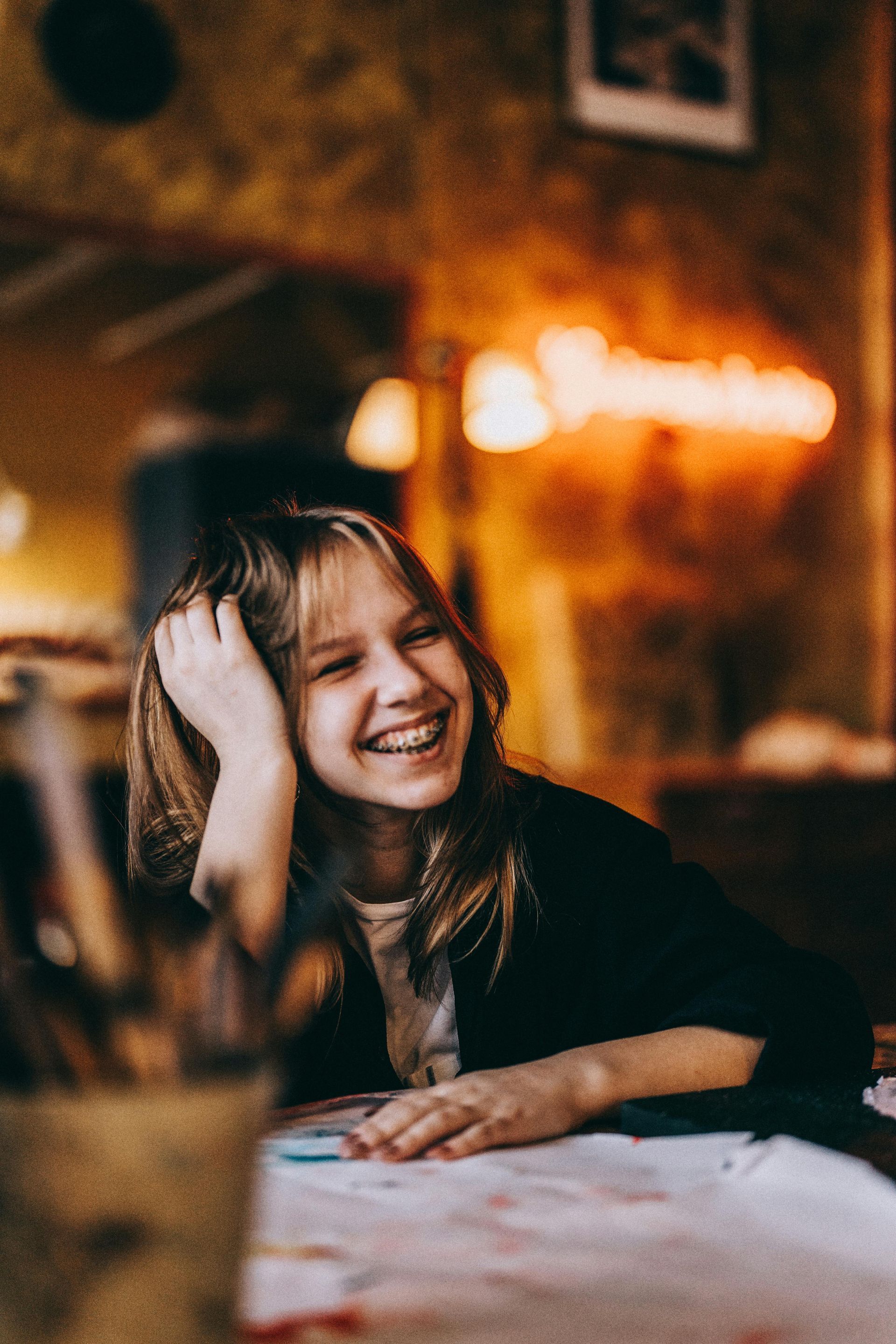 A young girl is smiling while sitting at a table in a restaurant.