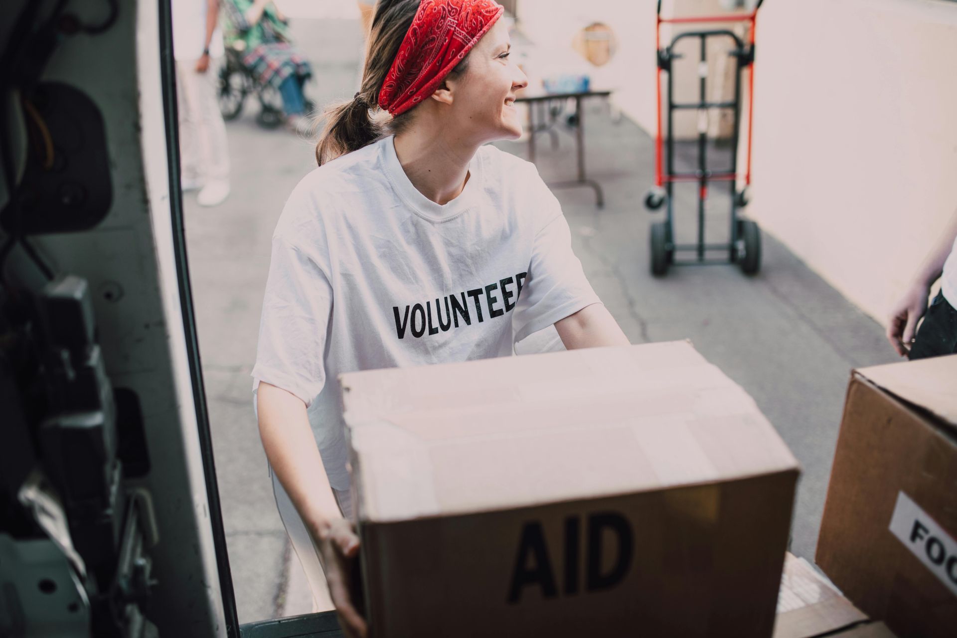 A woman in a volunteer shirt is carrying a box of aid.