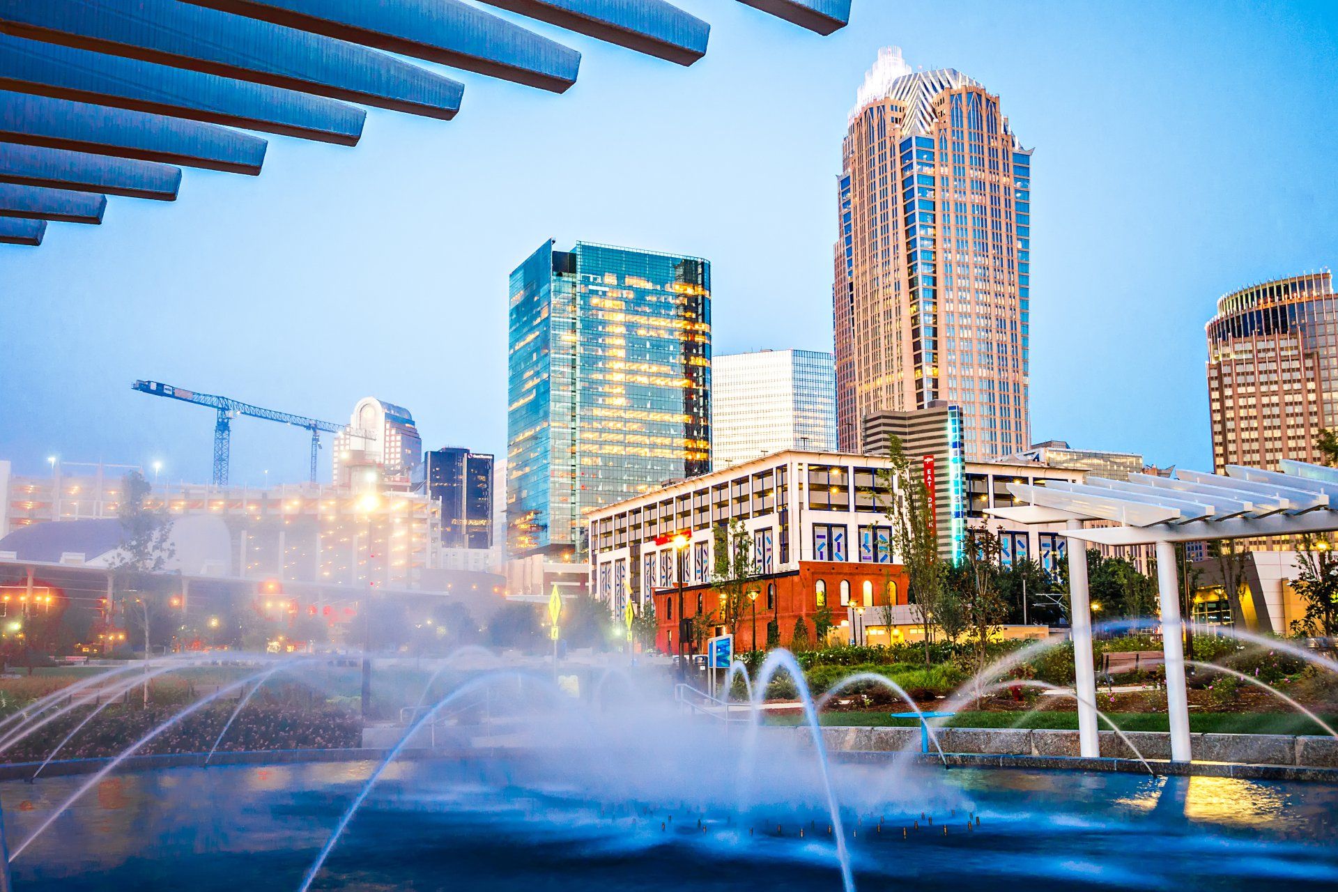 A fountain is spraying water in front of a city skyline at night.