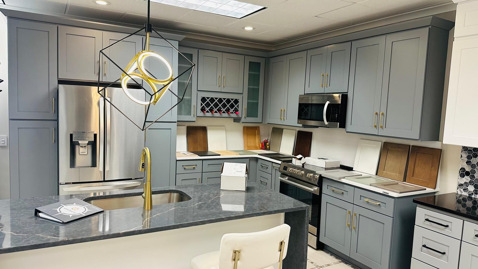 A kitchen with gray cabinets , granite counter tops , and stainless steel appliances.