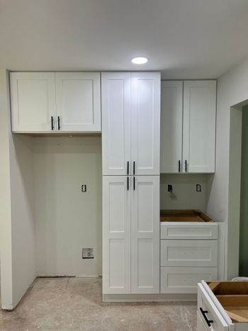 A kitchen with white cabinets and drawers and a sink