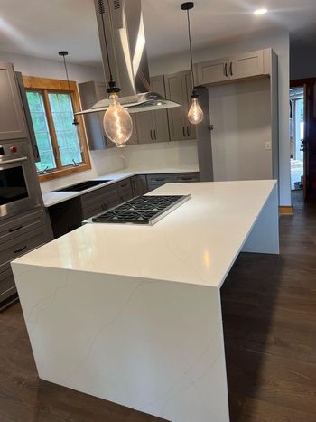 A kitchen with a large island and a stove top oven.