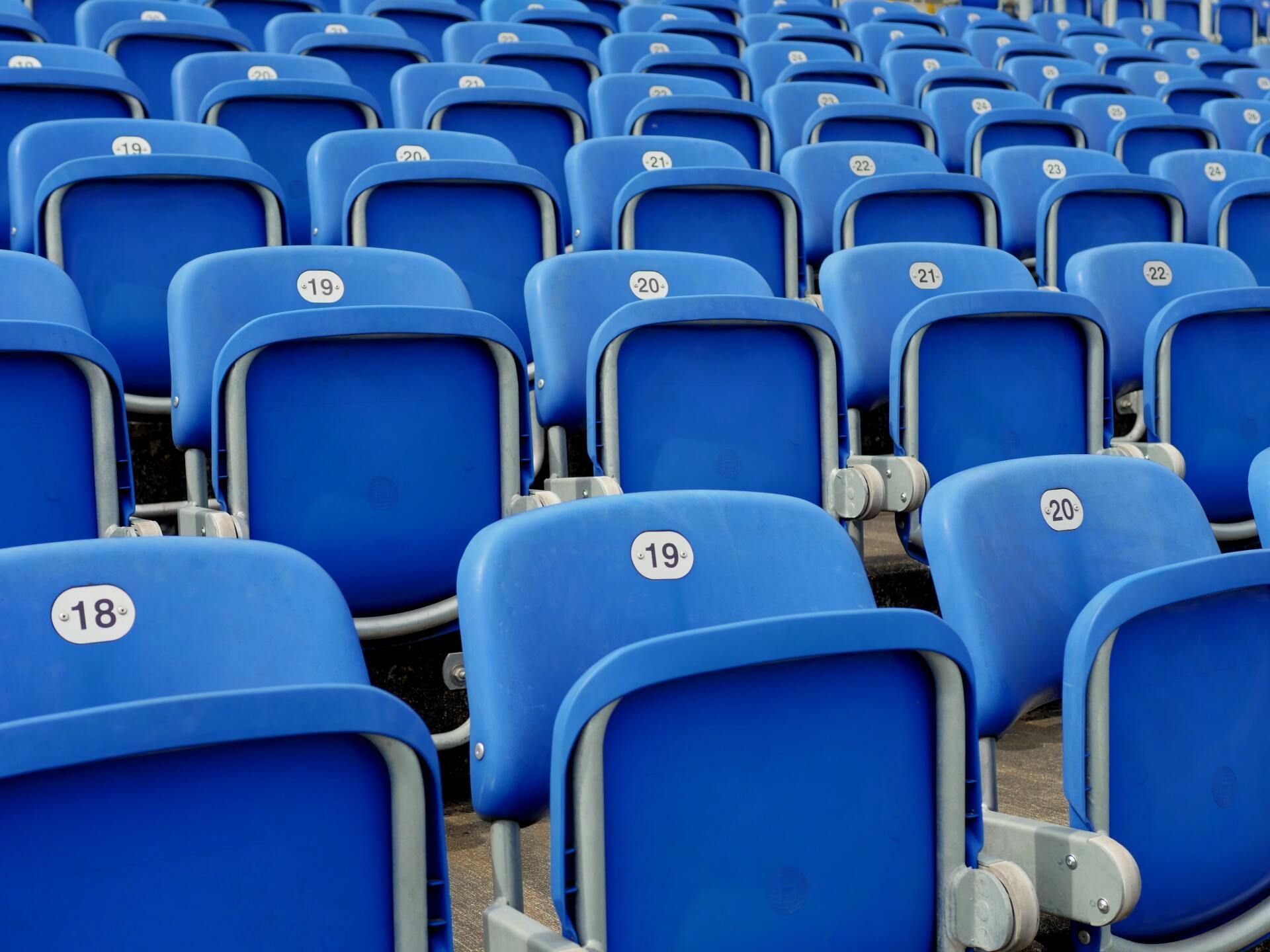 Rows of empty blue stadium seats with numbered backs.