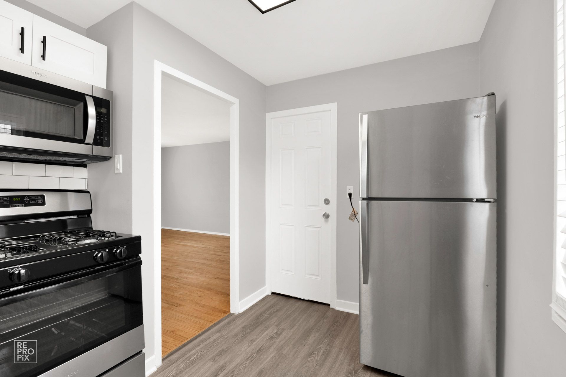 Kitchen with gray walls, stainless steel appliances, and a white door.