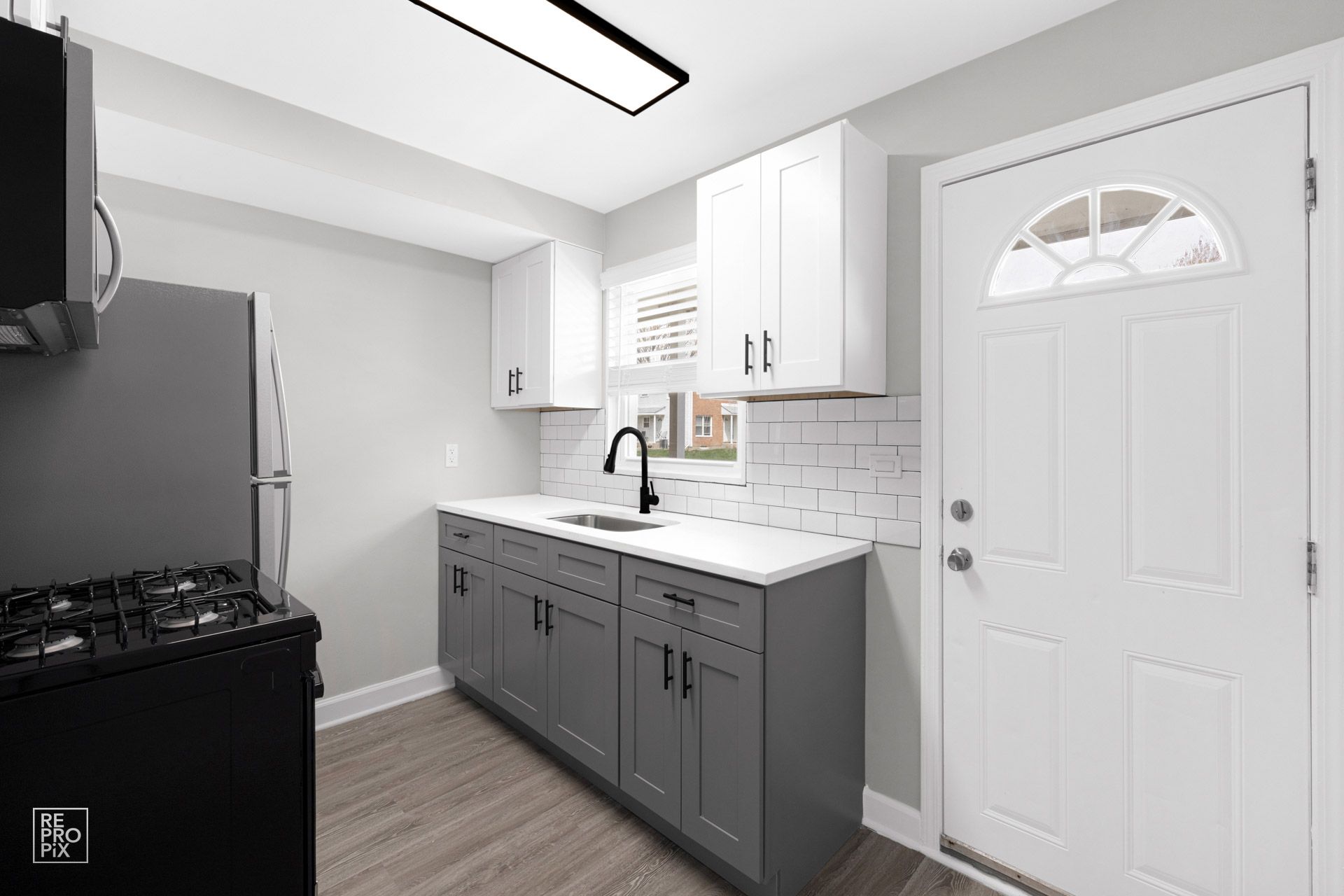 Kitchen with gray and white cabinets, white countertops, and a black stove and refrigerator.