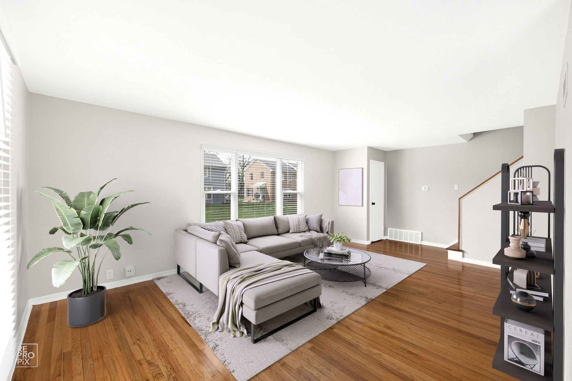 Living room with gray sectional, coffee table, plant, and wooden floors.