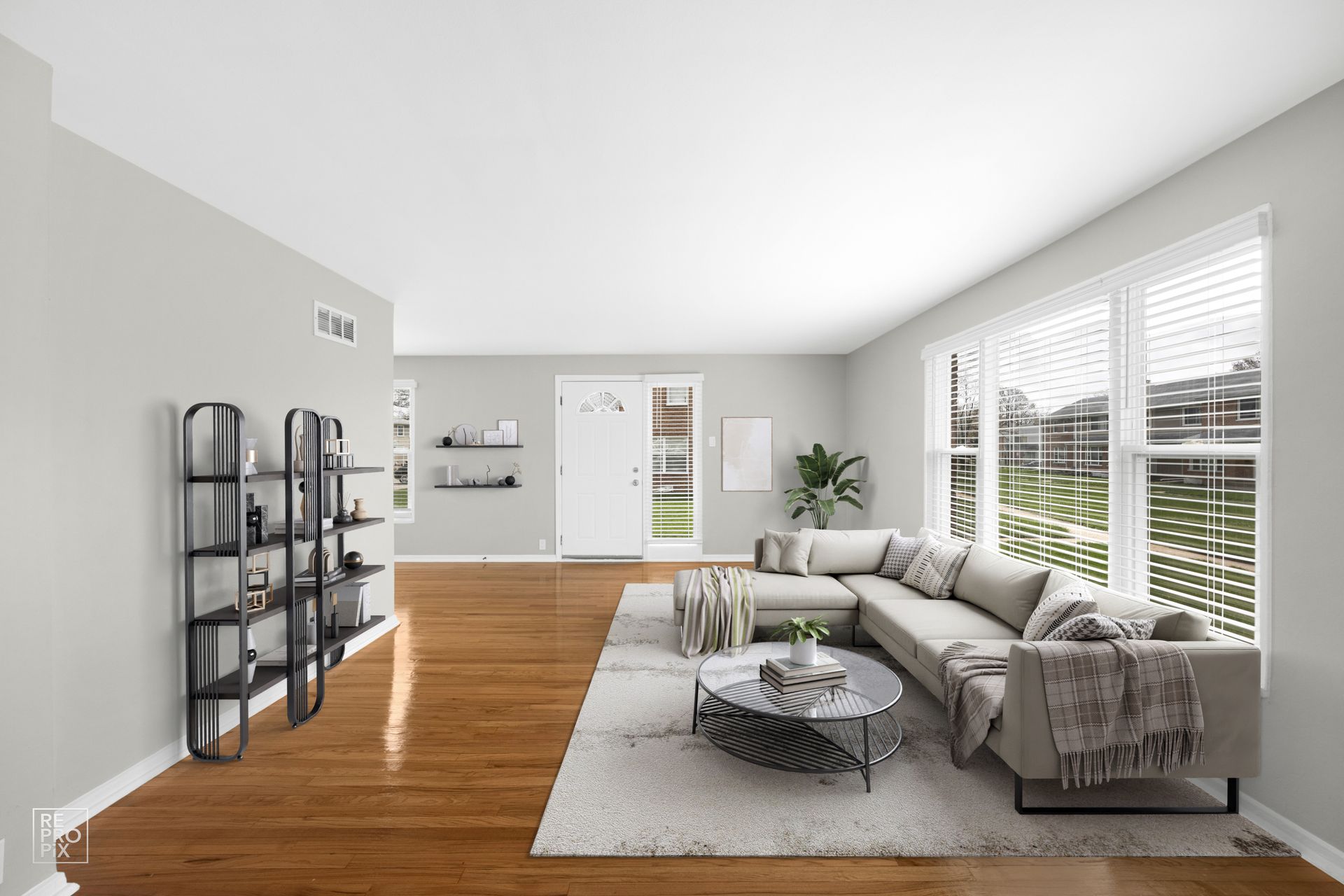 Living room with hardwood floors, gray walls, and a large sectional sofa by a window.