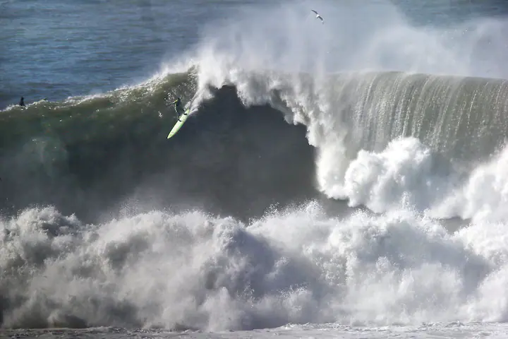 Ocean and surfers catching the wave on the Marevick's beach.