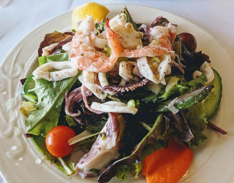 A plate of salad with vegetables and seafood at Mezza Luna Restaurant.