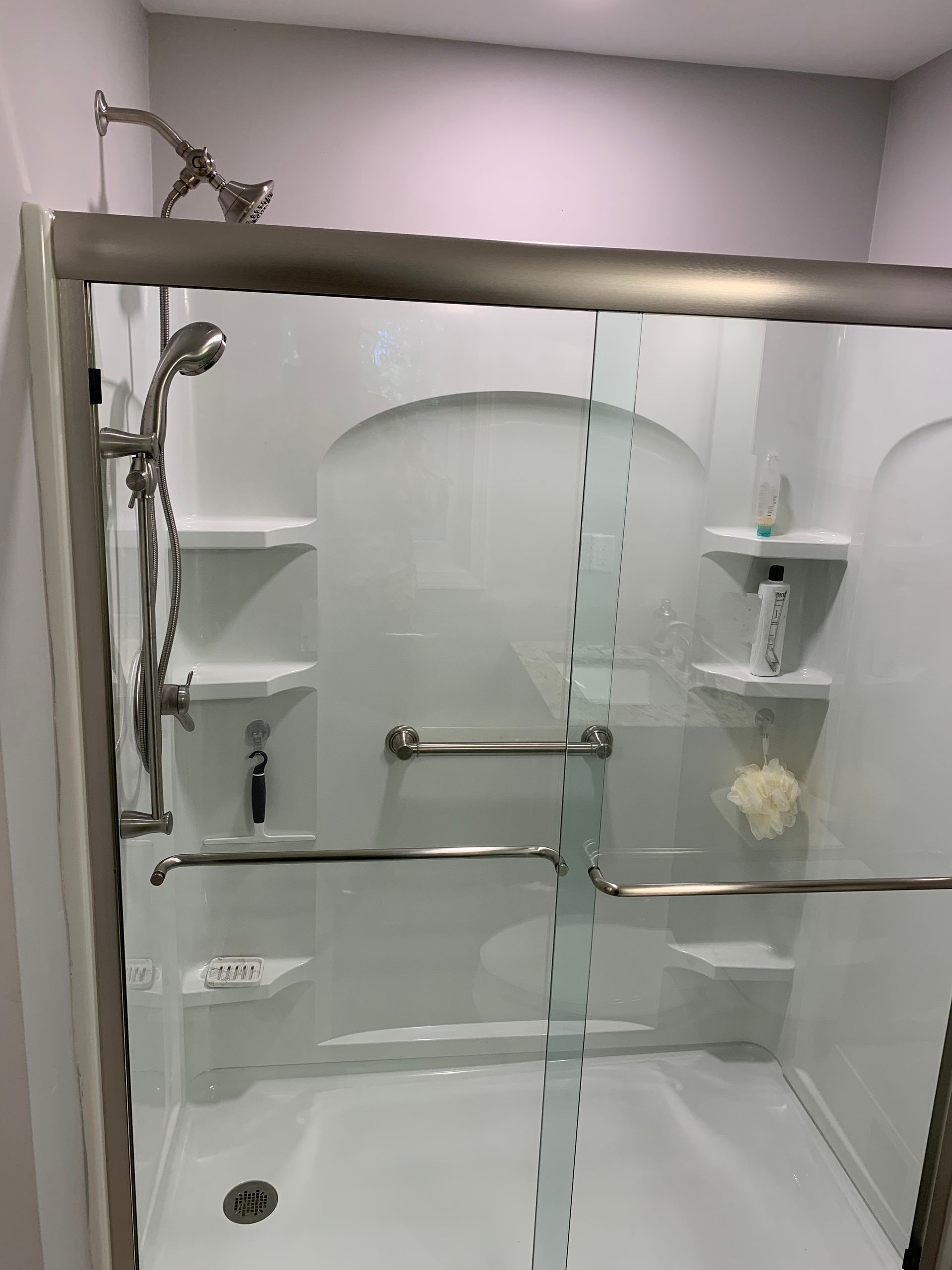 A shower with a sliding glass door and a shower head.