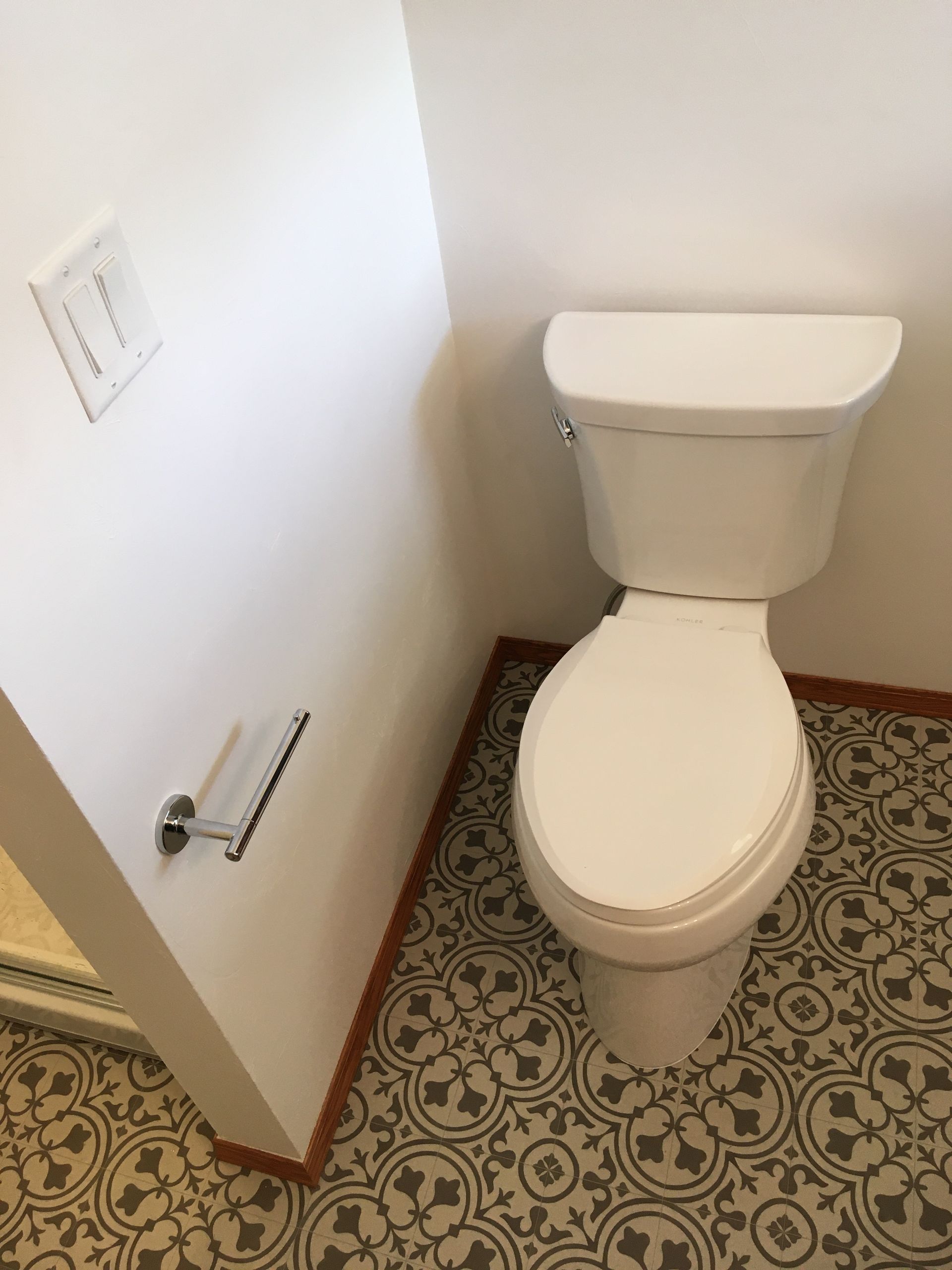 A white toilet is sitting in a bathroom next to a wall.