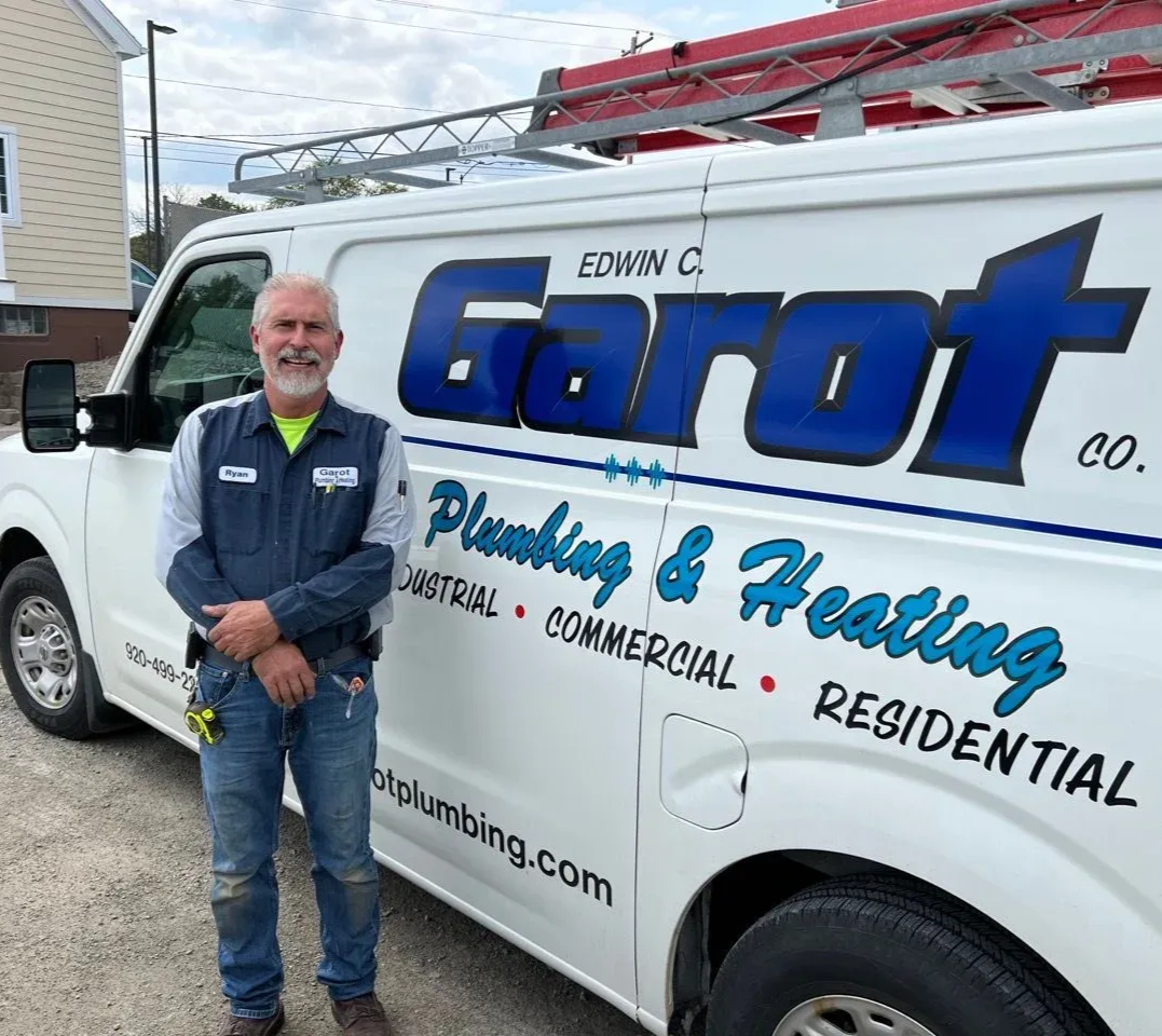 A water heater is sitting in a basement next to a wall.