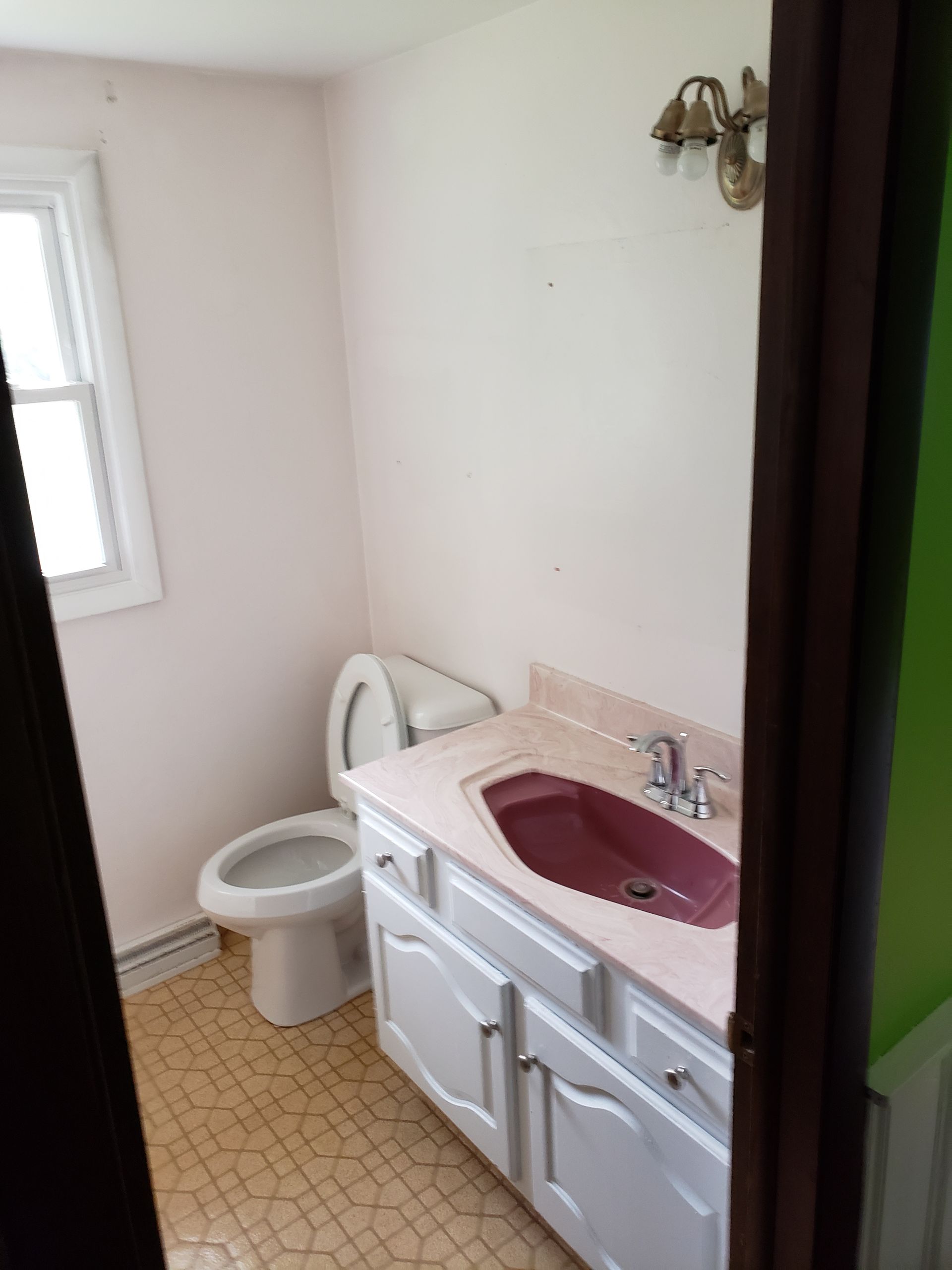 A bathroom with a toilet , sink and cabinets.