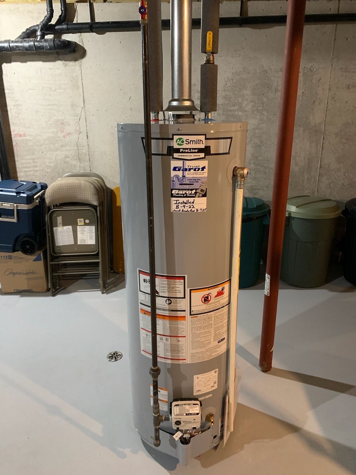 A water heater is sitting on the floor in a basement.