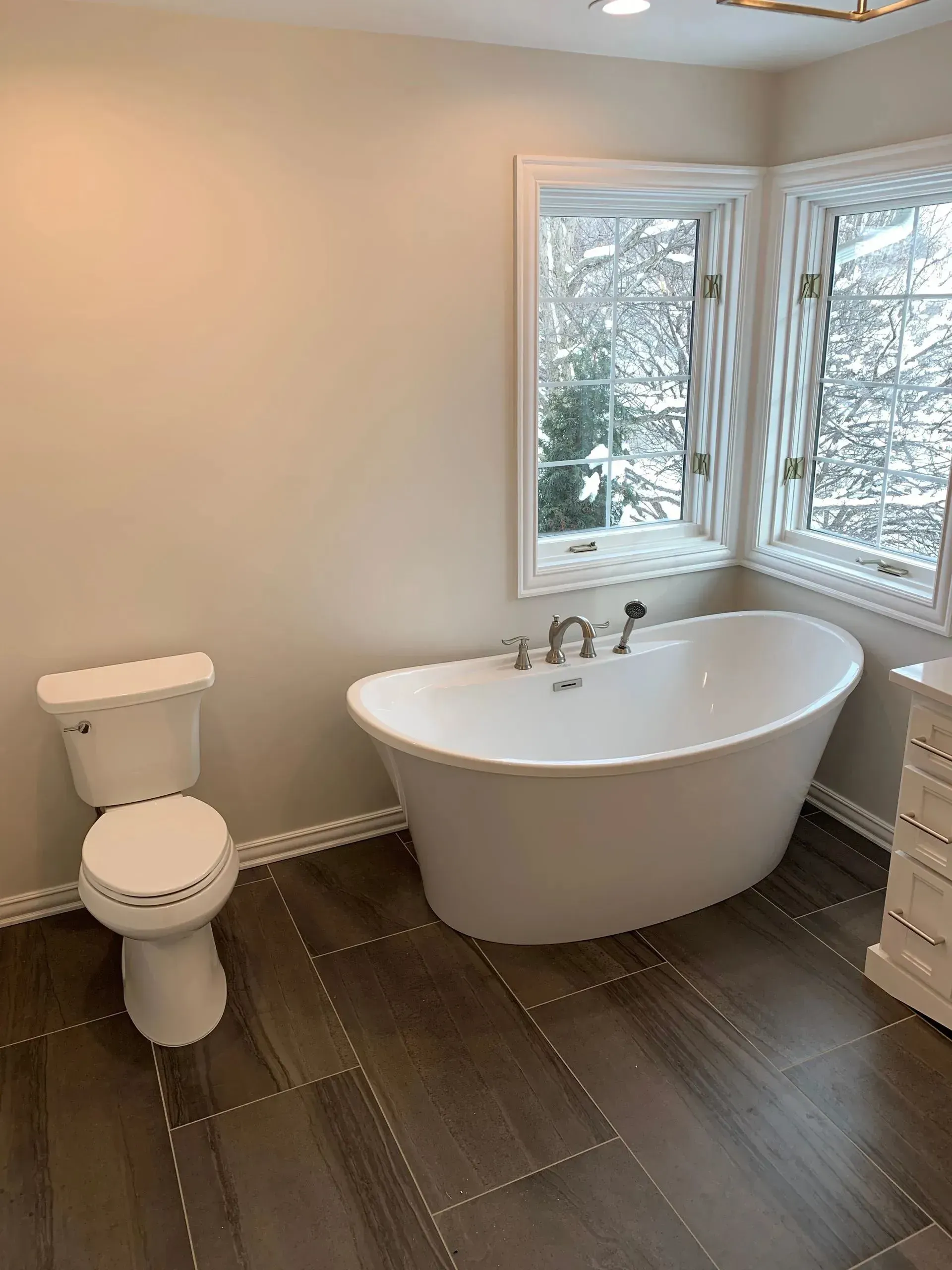 A bathroom with a tub , toilet , and window.