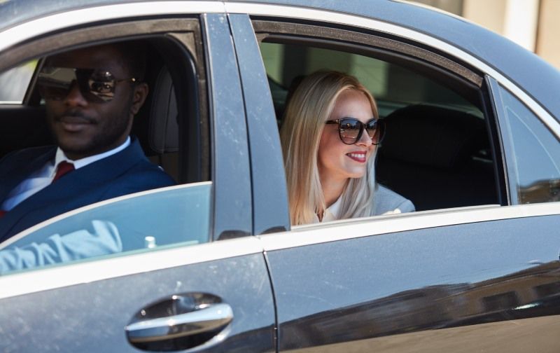 A man and a woman are sitting in a black car.