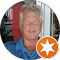 A man in a blue shirt is smiling in a circle with an orange star.