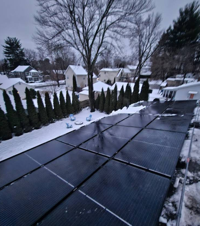 A row of solar panels on a roof in the snow