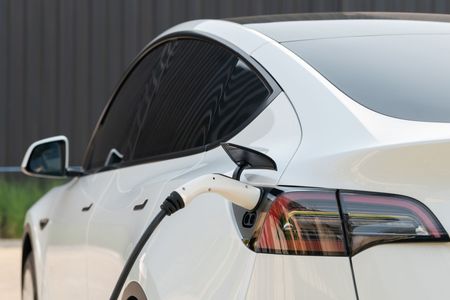 A white tesla model 3 is being charged at a charging station.