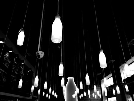 A black and white photo of a row of bottles hanging from the ceiling.