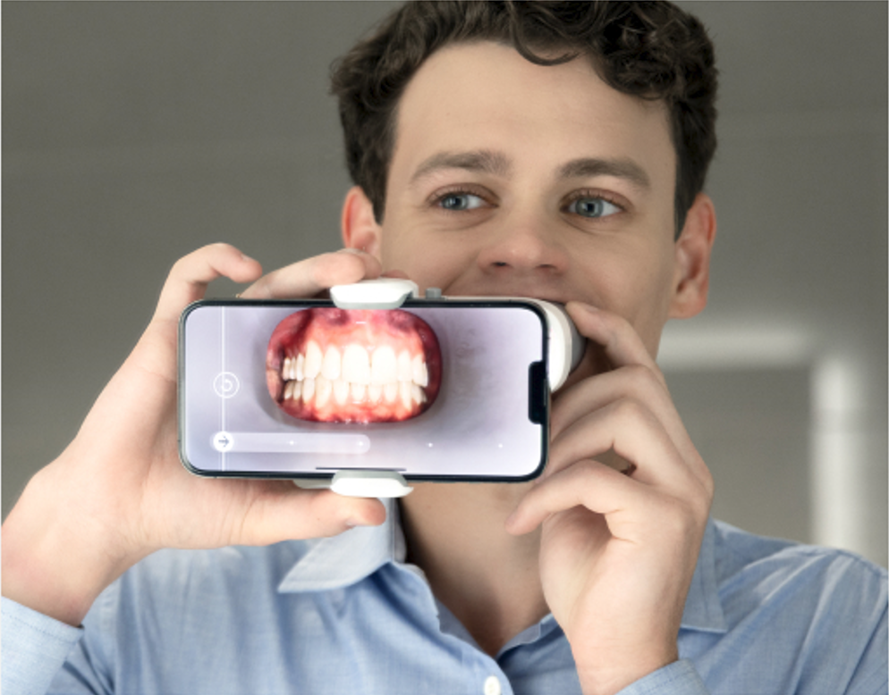 A man is taking a picture of his teeth on his phone