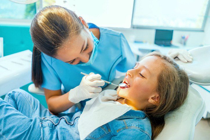 dental hygienist examining young patient teeth
