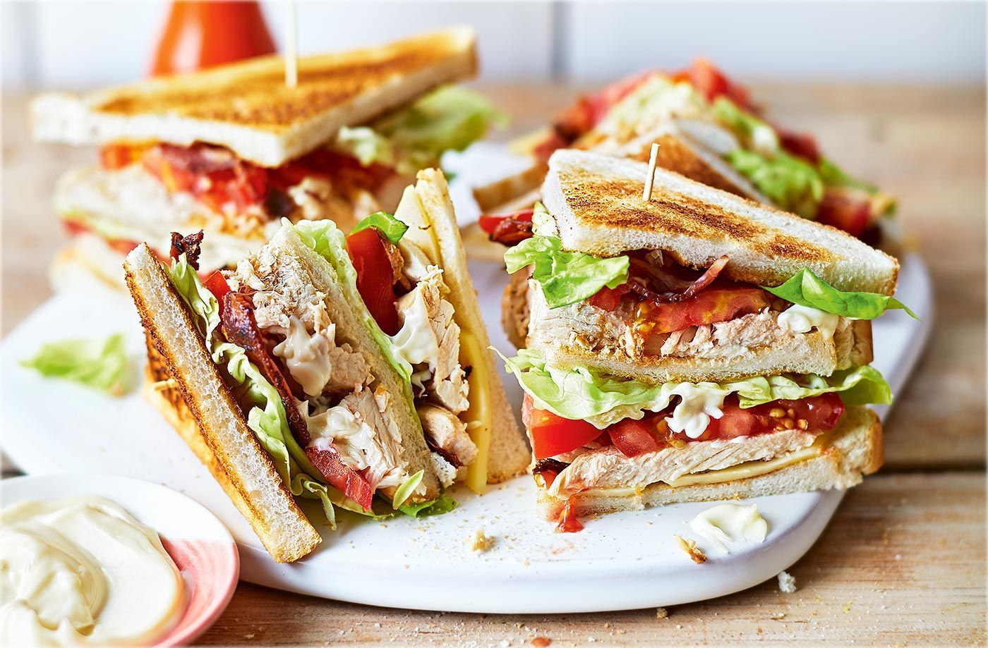 Three club sandwiches are stacked on top of each other on a white plate.