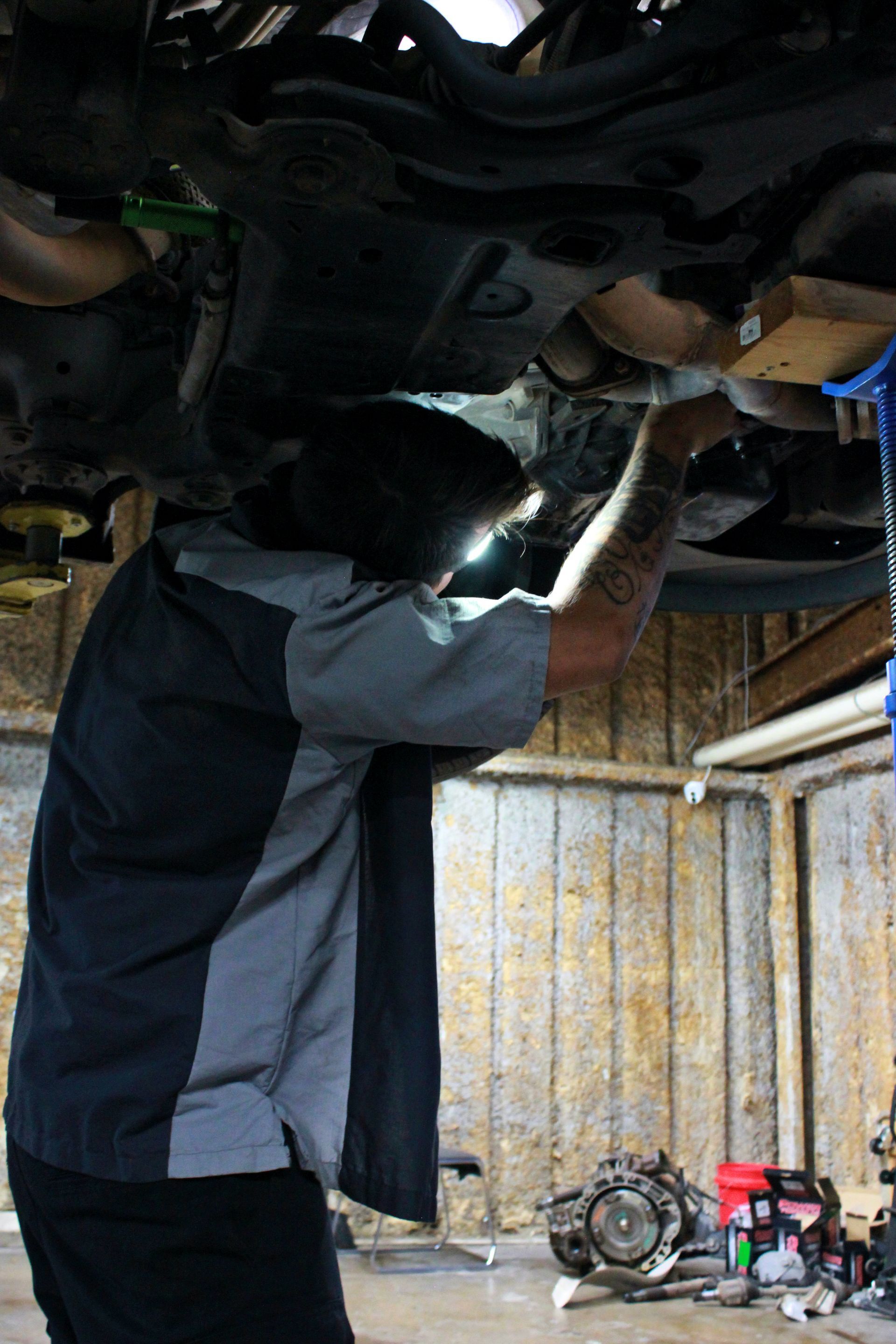 Mechanic working under a car, illuminated by a light. Workshop setting.