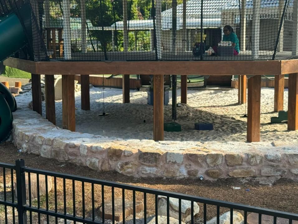 A Playground With A Slide, Swings, And A Fence Surrounding It — Australian Rock Walls In Hervey Bay, QLD