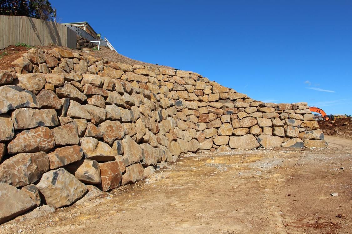 A Large Pile Of Rocks Is Sitting On Top Of A Dirt Hill — Australian Rock Walls In Byron Bay, NSW