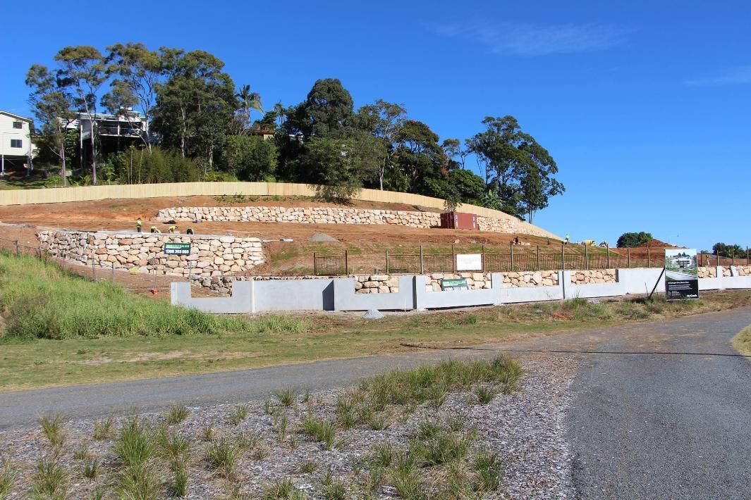 A Dirt Road Leading To A Hill With A House In The Background — Australian Rock Walls In Upper Coomera, QLD