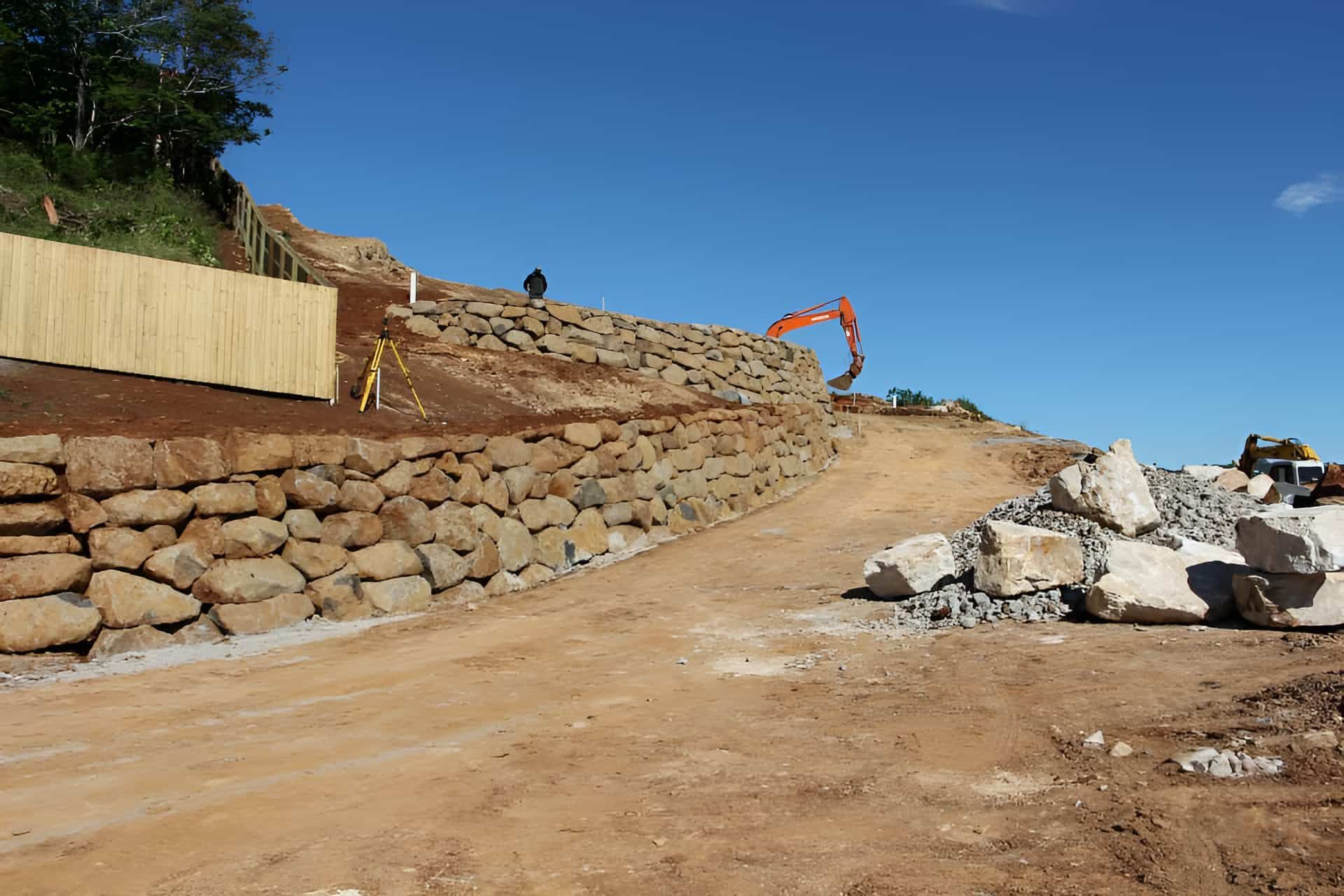 A Large Rock Wall Is Being Built On The Side Of A Dirt Road — Australian Rock Walls In Burleigh Heads, QLD