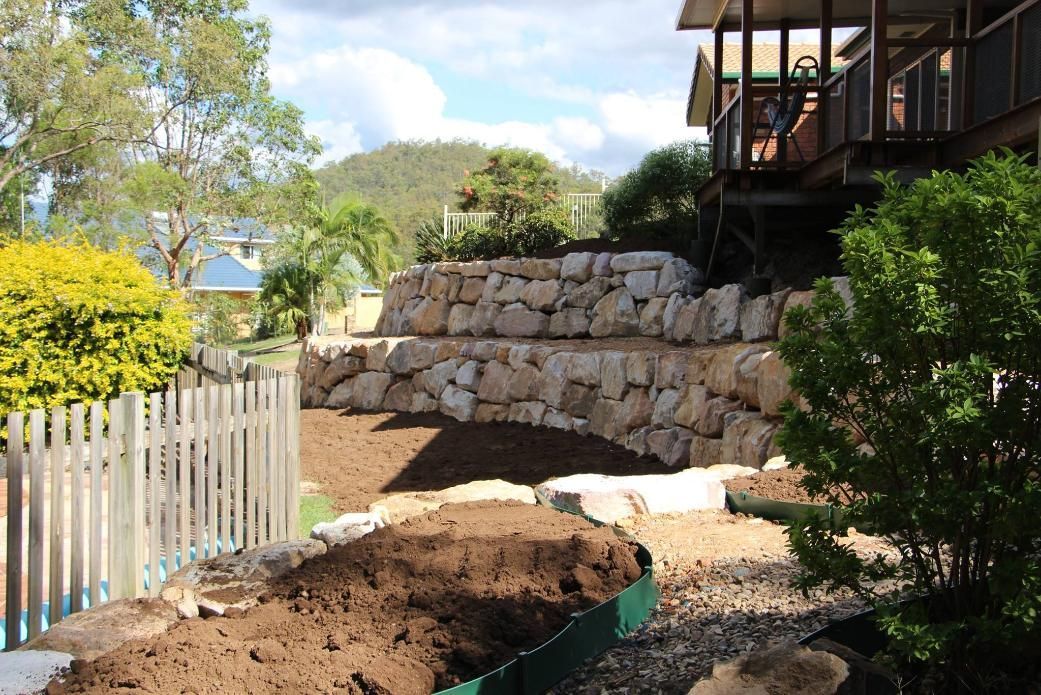 A Pile Of Dirt Is Sitting In Front Of A Stone Wall — Australian Rock Walls In Burleigh Heads, QLD