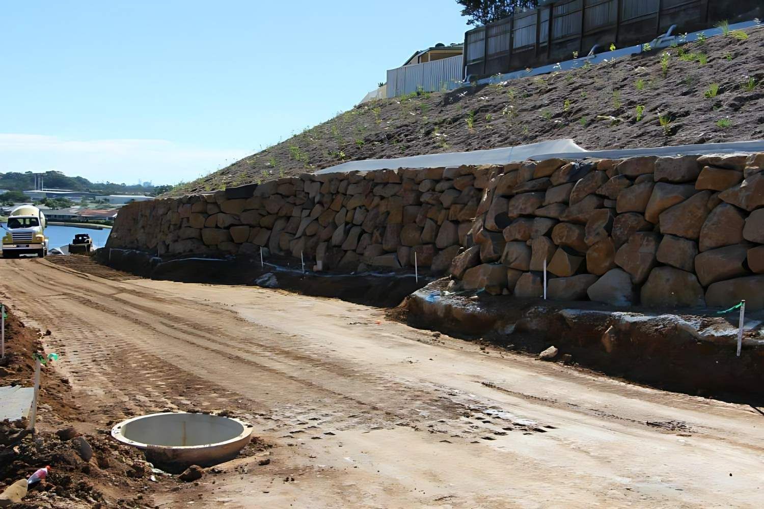 A Dirt Road With a Large Stone Wall in the Background — Australian Rock Walls In Burleigh Heads, QLD