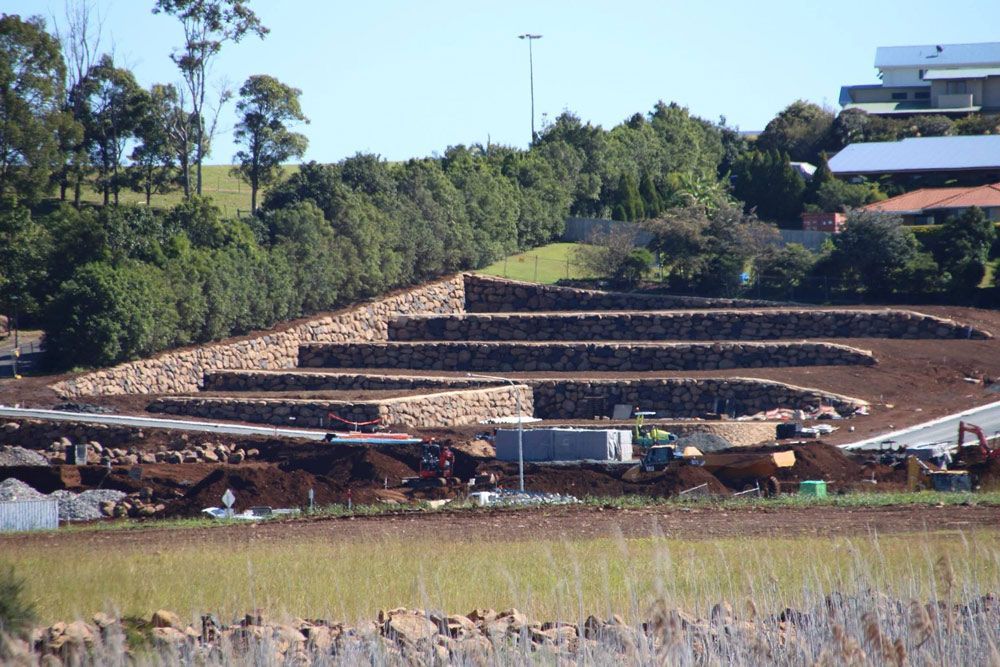 A Dirt Road With a Large Stone Wall in the Background — Australian Rock Walls In Burleigh Heads, QLD