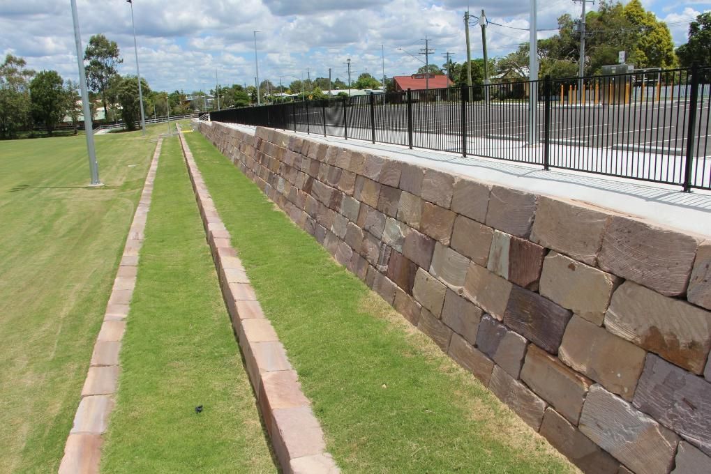 A Brick Wall Surrounds A Lush Green Field — Australian Rock Walls In Burleigh Heads, QLD