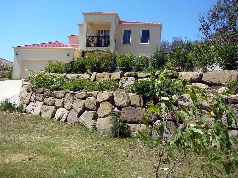 A Large House With a Stone Wall in Front of It — Australian Rock Walls In Burleigh Heads, QLD