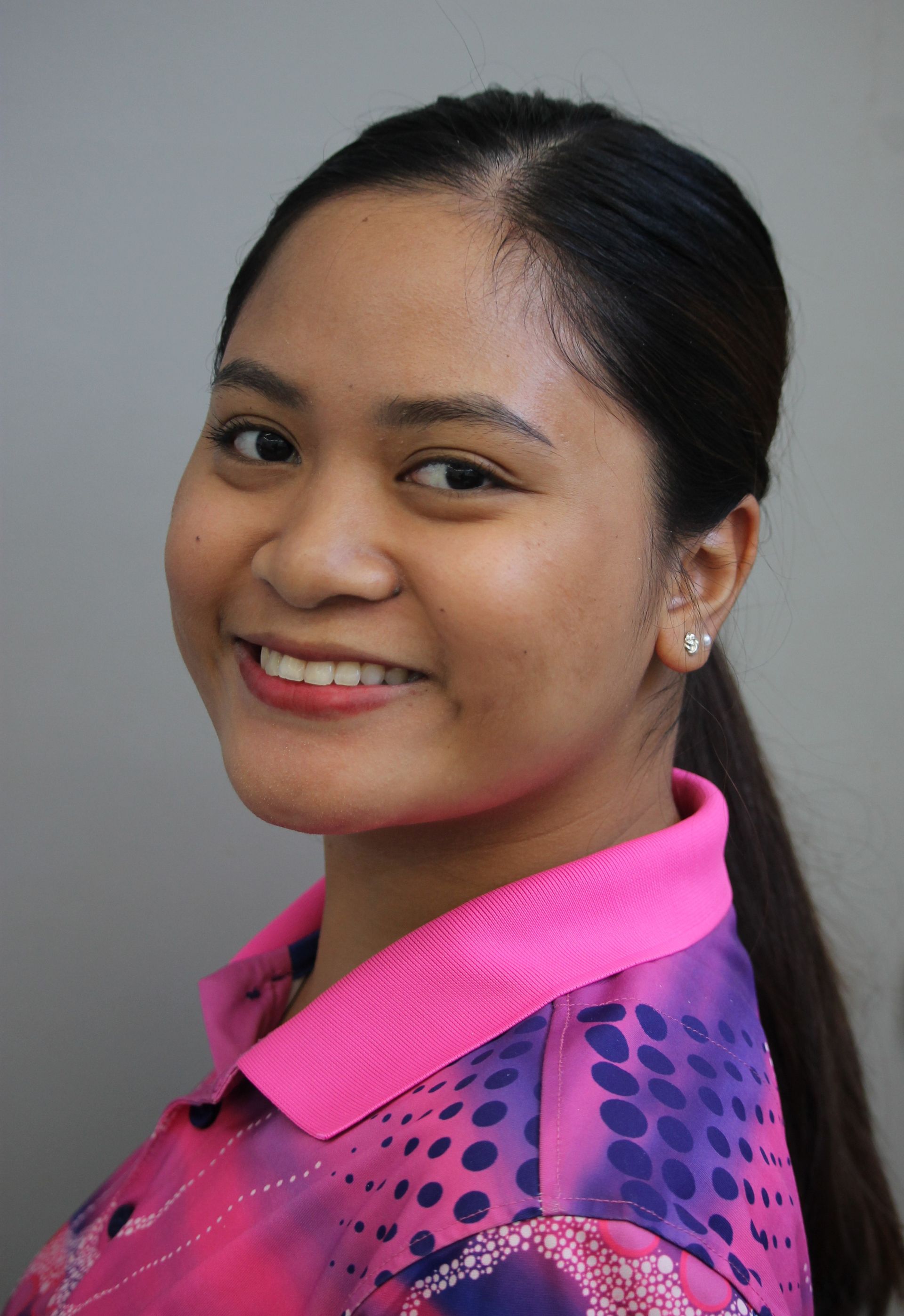Smiling woman with dark hair pulled back, wearing a pink collared shirt.