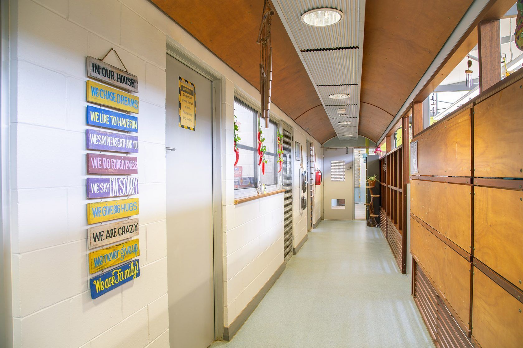 Hallway with doors, windows, and signs. Brown and white walls, light floor.