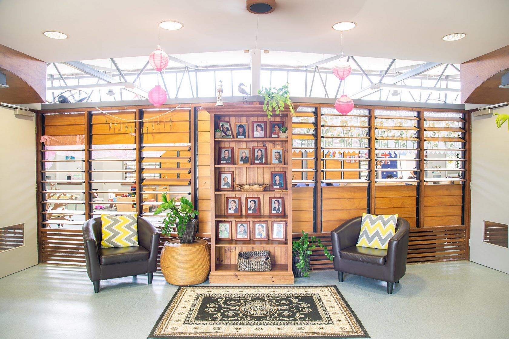 Lounge area with wooden accents, two armchairs, bookcase, and a decorative rug.